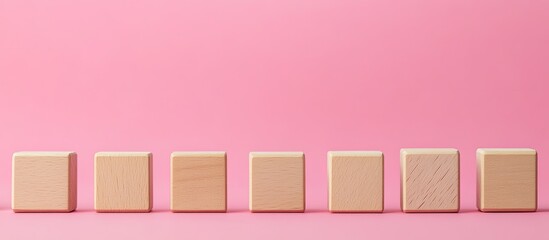 Poster - Wooden blocks arranged in a row on a pink background with ample copy space for text or design elements showcasing a conceptual representation.