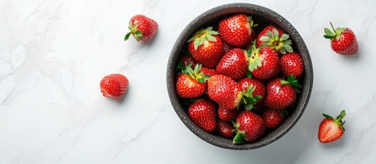 Poster - Fresh ripe strawberries in a black bowl positioned at the center on a marble surface with scattered strawberries around creating a vibrant display