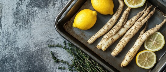 Poster - Baking tray with uncooked salsify roots, fresh lemons and thyme, positioned on a grey wooden table, featuring vibrant yellow and earthy tones.