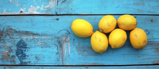 Poster - Fresh ripe lemons arranged on weathered blue wooden surface with rustic texture showcasing vibrant yellow color against the calming blue backdrop.