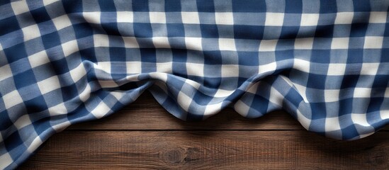 Aufkleber - Blue and white checkered tablecloth gracefully draped on a rustic wooden surface with natural grain patterns, captured from a top view angle.