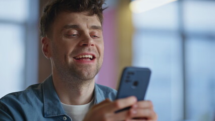 Poster - Smiling guy typing sms on mobile phone in office closeup. Man enjoying break