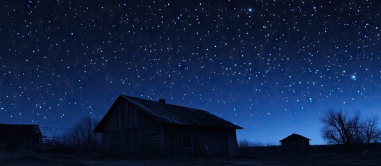 Wall Mural - Starry night sky illuminating a rustic house silhouette with deep blue tones and twinkling stars in the background creating a tranquil atmosphere.