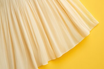 Poster - Soft cream fabric laying flat against a vibrant yellow background showcasing texture and elegance in clothing design