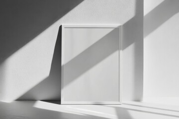 Poster - Blank white vertical poster frame against minimal white wall with soft shadows and indirect light reflections