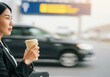 © SERHII - Woman at airport holding coffee cup with blurred traffic in background