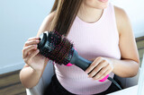 Mujer usando cepillo secador y modelador eléctrico Alisado de cabello. 