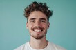 © Markus Schröder - Portrait of a content man in his 20s smiling at the camera isolated on soft teal background