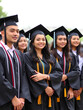 © Ann - Hispanic college graduates standing together in caps and gowns