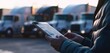 © BlueJay - Truck driver navigating logistics with tablet near parked semi trucks, digital workflow concept