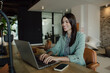 © Jovan - Smiling Professional Woman Working on Laptop in a Modern Office Setting