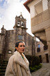 © asier - Fashionable traveler strolling cobblestone pathways of combarro, classic galician village featuring historic stone houses, waterfront setting, traditional church backdrop