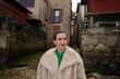 © asier - Tourist in a stylish beige coat and green shirt wandering the charming streets of combarro, a historic coastal town in galicia, spain, soaking in the local culture