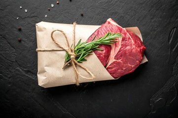 Poster - A beautifully arranged piece of meat wrapped in brown paper tied with twine, garnished with a sprig of rosemary.