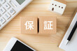 © ELUTAS - 保証と書かれたブロック、電卓、家のおもちゃ