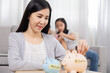 © Rakchanok - Asian mother put coins in piggybank saving money for medication and education for children lifestyle concept, well organize planning of single mom with two kids for finances and house expenses