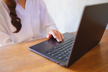 Wall Mural - closeup image of a woman working and touching on laptop computer touchpad