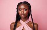 Attractive dark-skinned girl with creative braids hairstyle, full face makeup, pink outfit on pink background. Young beautiful model expresses natural charm, ethnic beauty, fashion trends. Studio
