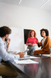 © NDABCREATIVITY - Young businesswoman leading a discussion during a meeting with her colleagues.