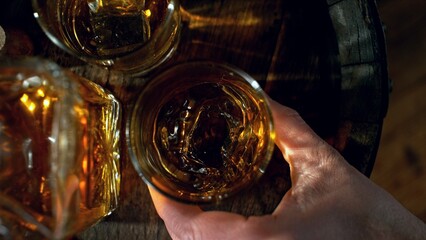 Poster - Detail of man hand holding whiskey drink. Freeze motion of drink preparation.