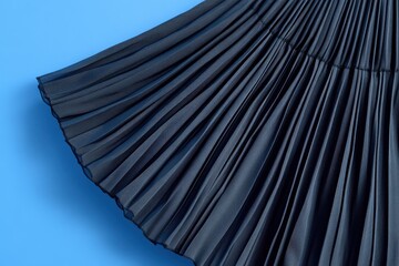 Poster - Elegant pleated fabric in dark color displayed against a vibrant blue backdrop for textile and fashion enthusiasts