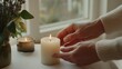 © VK Studio - Hands place a lit candle beside another in a peaceful indoor setting, creating an atmosphere of warmth and reflection.