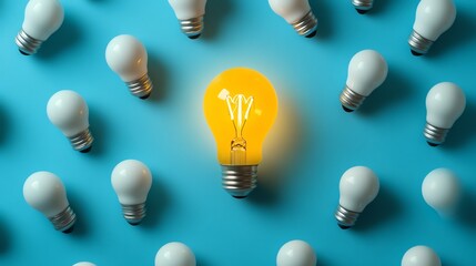 Leinwandbilder - A glowing yellow light bulb surrounded by white bulbs on a blue backdrop, illustrating creativity, innovation, and the illumination of new ideas
