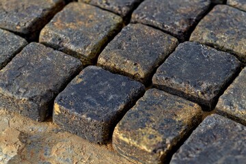 Poster - close-up of dark gray cobblestone pavement texture, showcasing weathered stone blocks with earthy to