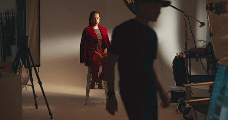 Poster - Photography, set and model on stool in studio with production team for creative magazine. Fashion, equipment and gen z female influencer posing on chair for portfolio photoshoot with art agency.