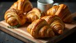 © Husen - Golden croissants, wooden cutting board, ceramic coffee cup, moody lighting, dark background, rustic kitchen setting, fresh baked pastries