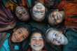 © kristina - Children sitting in a circle, holding hands and laughing together, under a vibrant rainbow-colored parachute during outdoor playtime.