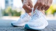 © Ulia_photo - A man ties his white sneakers before a run.