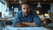 © ZpongXED - A focused man with a beard sits at a desk, looking contemplatively at blueprints in a well-lit workspace.