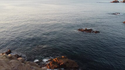 Wall Mural - Calm Ocean Waters Embrace Rocky Shores at Sunset, Creating a Peaceful and Serene View for Nature Lovers and Adventurers Alike.