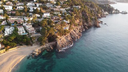 Wall Mural - Beautiful coastline view of a peaceful beach and rocky cliffs. This image captures a stunning sunset over seaside homes by the shoreline in a tranquil setting.