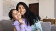 © fizkes - Loving mother cuddling tightly her cute little 5s daughter. Preschooler girl enjoy playtime and tender moments with young beautiful mum seated together on sofa at home, feeling love, express affection