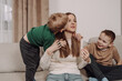 © ibilyk13 - A happy mother embraces her children in a warm, homey atmosphere. The younger boy kisses her cheek, while the older one smiles joyfully. A natural, heartfelt family moment full of love and closeness.