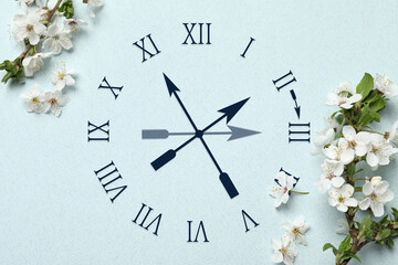 Poster - Clock and blossoming branches with white flowers on light blue background, top view. Arrow showing time change one hour ahead in spring. Daylight saving time