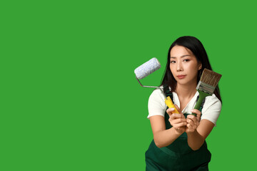 Wall Mural - female asian painter with roller and brush on green background
