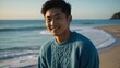 © Alteisen Riese - Good-looking young asian guy in blue themed sweater on a beach smiling
