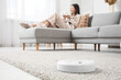 © Pixel-Shot - Robot vacuum cleaner on carpet against woman drinking coffee at home, closeup