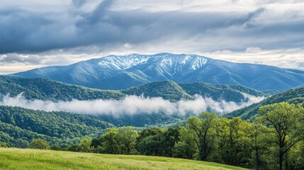 Leinwandbilder - Scenic landscape of misty snow capped mountains over green hills under a dramatic sky