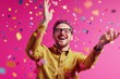© BerkahStock - Happy man celebrating with confetti falling around him against a pink background.