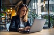 © vefimov - A focused business woman sitting at a desk using a laptop.
