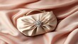 © Artittaya - A diamond clutch bag resting on a silky pink fabric with soft folds and shadows.