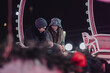 © qunica.com - A couple sits closely together on a Ferris wheel at night, sharing a moment. The surroundings highlight a festive and cozy atmosphere, enhanced by the warm and intimate bokeh lighting.