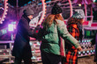 © qunica.com - Cheerful friends in warm clothing have a fun evening at a carnival during winter, enjoying festive lights and lively amusement rides under the glowing fairy-tale atmosphere.