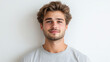 © NaphakStudio - young man with wavy hair and friendly smile, wearing gray t shirt against light background.