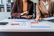 © Phushutter - Two female business professionals in suits sit at desk, engaged in strategic discussion. They analyze financial planning, risk management, corporate growth while reviewing reports and market trends.