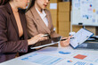 © Phushutter - Two female business professionals in suits sit at desk, engaged in strategic discussion. They analyze financial planning, risk management, corporate growth while reviewing reports and market trends.